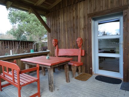 zeigt Terrasse am Haus mit Sitzmöbeln