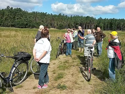 Lesestübchen zeigt Personen mit Fahrrädern auf einem Wiesenweg