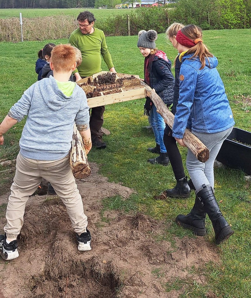 zeigt Kinder beim Aufstellen des Insektenhotels