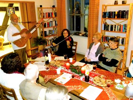 Lesestübchen zeigt mehrere Personen um einen Tisch herum, von denen einige Instrumente spielen