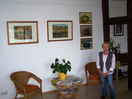 Lesestübchen zeigt Ausschnitt einer Bilderausstellung mit einer Frau davor