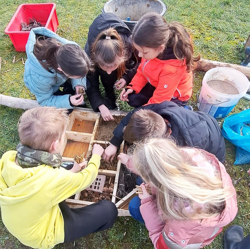 zeigt Kinder beim Befüllen des Insektenhotels