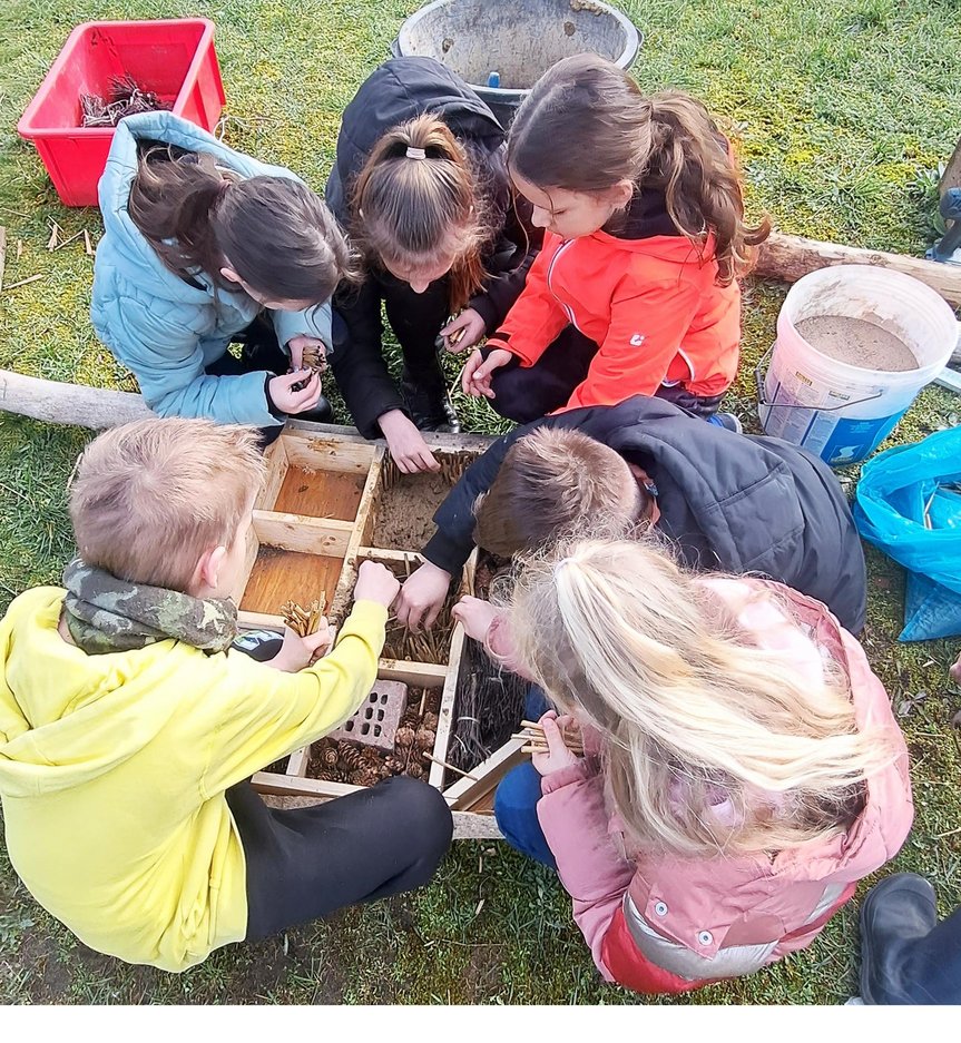 zeigt Kinder beim Befüllen des Insektenhotels