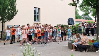 zeigt Schulkinder beim Singen des Begrüßungsliedes