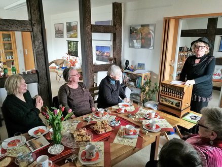 Lesestübchen zeigt Frauen an einer Kaffeetafel mit einer Rednerin am Kopf des Tisches
